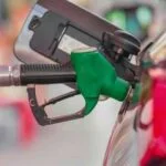 Bico de abastecimento de combustível sendo inserido em carro, representando comparação entre gasolina e álcool para economia de custos.