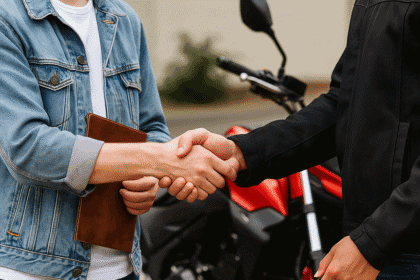 Aproximação de duas pessoas dando um aperto de mão, uma delas segurando as chaves de uma moto, simbolizando negociação, venda ou transferência de bens em economia pessoal.