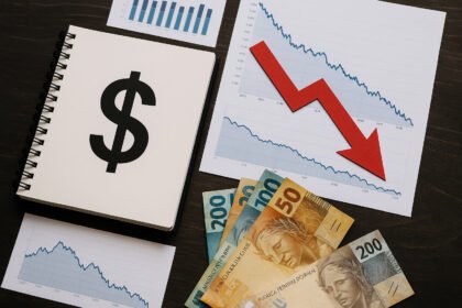 Imagem mostra gráfico de queda do dólar e dinheiro em reais, refletindo a recente desvalorização do dólar frente ao real, atingindo o menor nível em 17 meses.